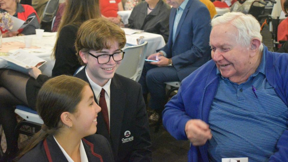 two genesis college students chatting with aged care resident