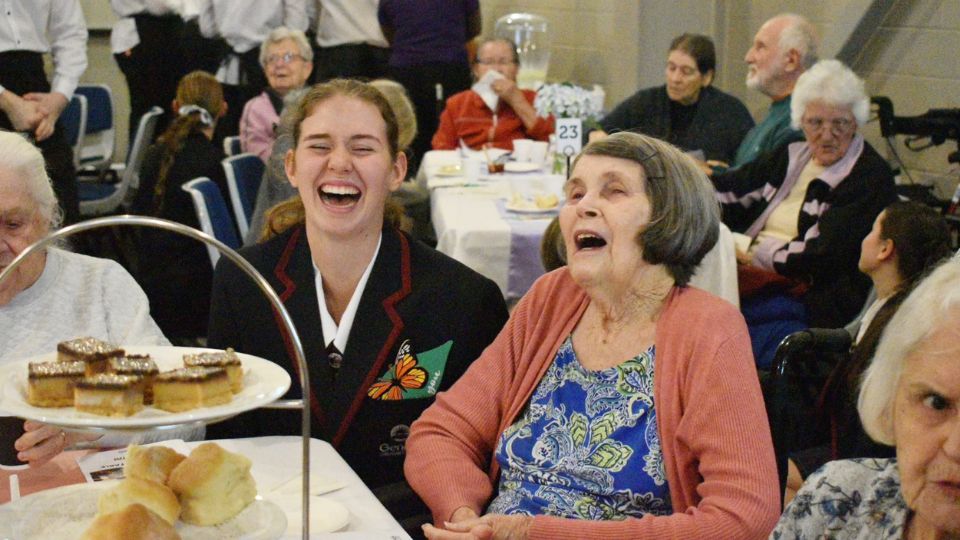 genesis college student laughing with aged care resident