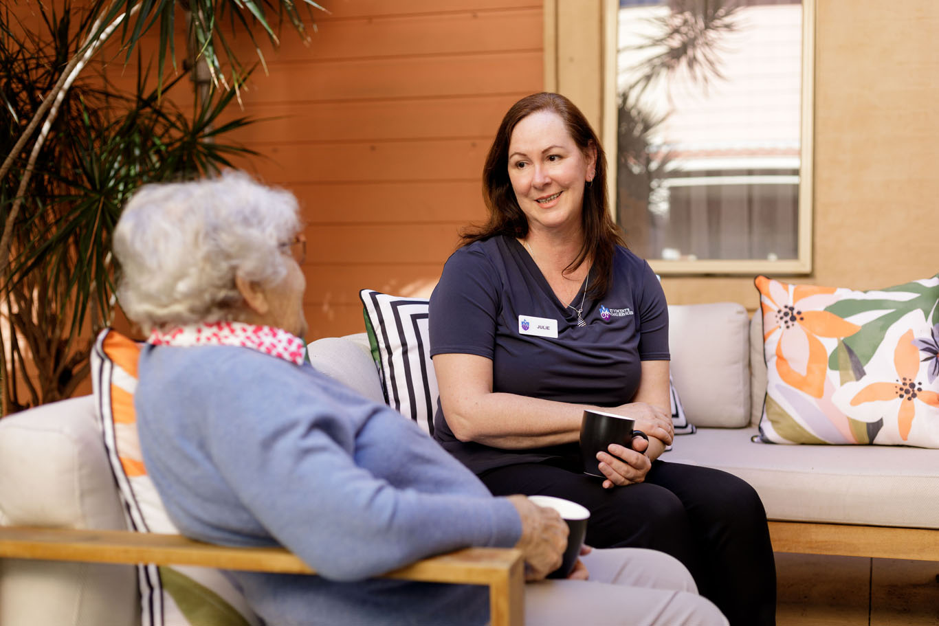 aged care worker with a resident sitting on an outdoor lounge