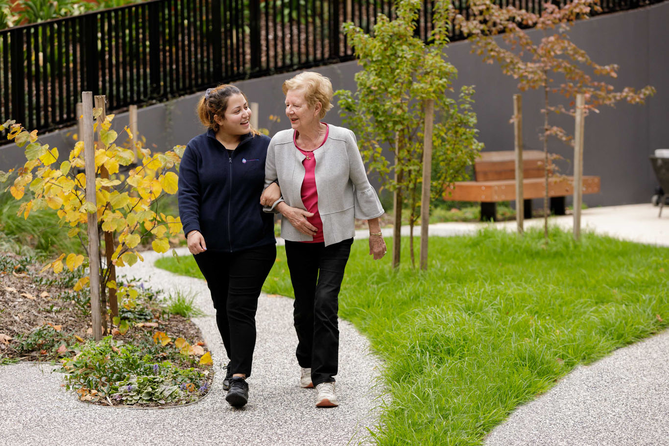 an aged care worker and staff member walking through gardens