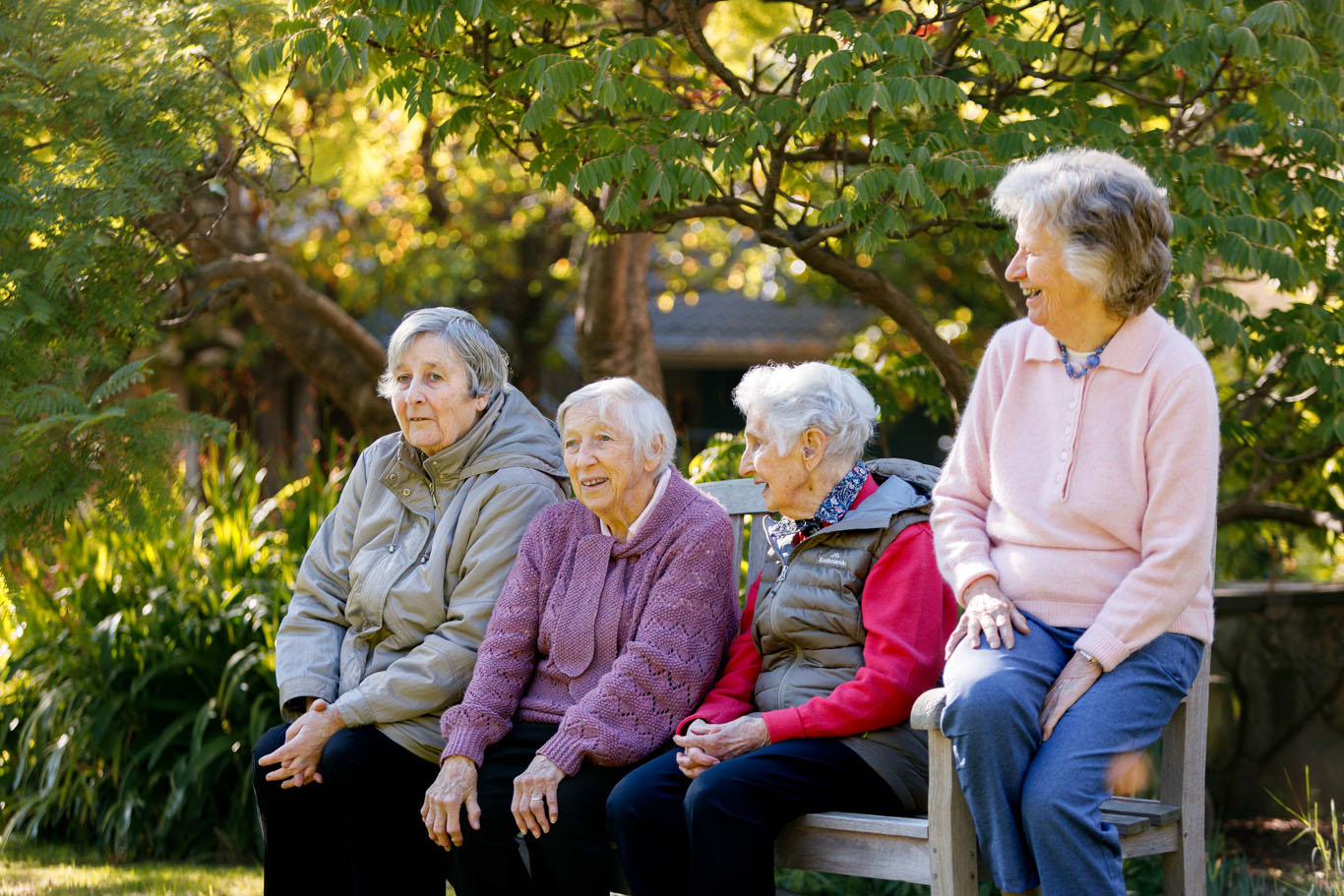 a group of aged care residents sitting next to each other on a park bench in hawthorn